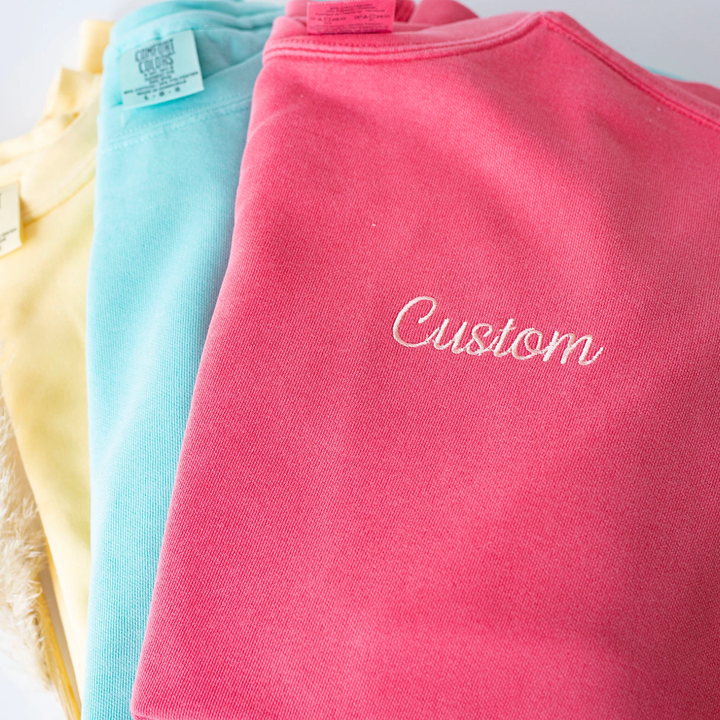 colorful embroidered sweatshirts folded on top of each other