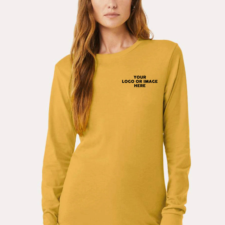 A woman wearing a mustard long sleeve t-shirt with featuring a custom logo